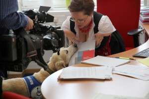 Assistenzhund reicht Hedi Menge eine Mappe.